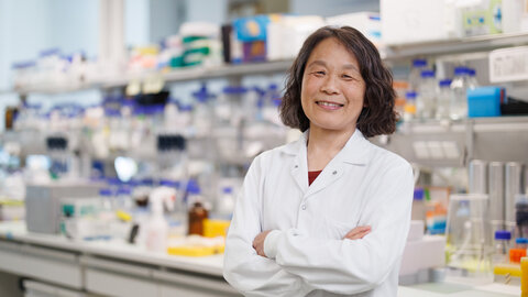 Porträt der US-amerikanischen Biochemikerin Elly Tanaka im weißen Kittel im Labor 