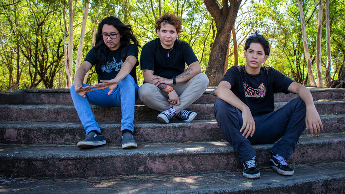 Drei junge Männer sitzen auf einer Steinstiege im Park 