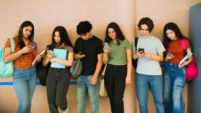 Endless scrolling—six teenagers are standing in a line, engrossed in their phones