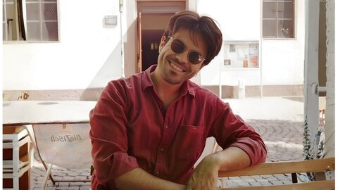 Portrait of a young researcher wearing sunglasses and a red shirt in an outdoor square