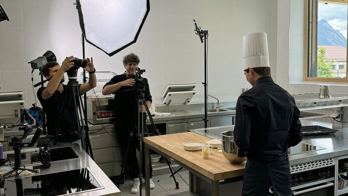 Two cameramen shoot a cooking video with pupils in the school kitchen