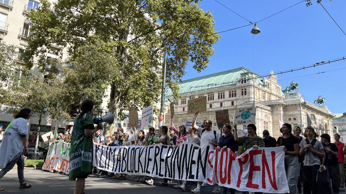 Demonstration march along Vienna's Ringstrasse with a long banner reading “Stop climate blockers”