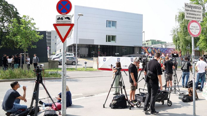 Gegenüber eines Schulgebäudes, warten Medienleute mit Kameras und Fotoapparaten auf Live-Übertragungen