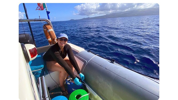 Young woman in a boat at sea extracts DNA from whales
