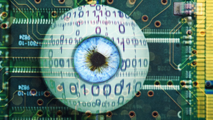 Symbol photo with artificial eye in front of a printed circuit board in green-yellow, the binary code 0 1 floats in front of the eye