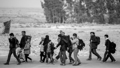 Migrants - a group of adults and children walking walking through a dry steppe region