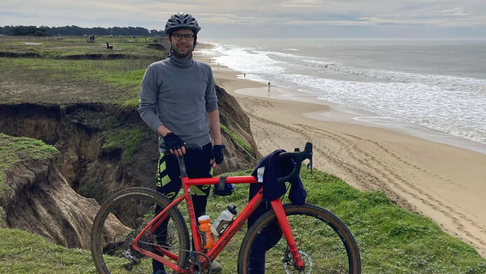 Young man in sports outfit and with mountain bike on the beach.