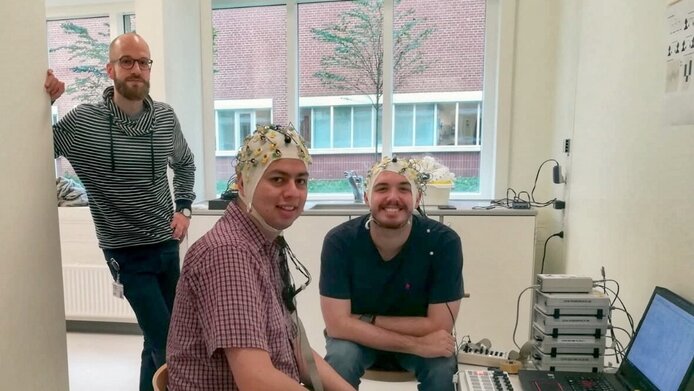 Vorführung eines der EEG-Paradigmen die am Center for Music in the Brain verwendet werden. Jan Stupacher im Hintergrund mit zwei Kollegen.
