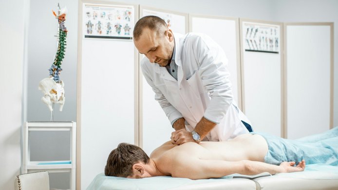 A physical therapist is treating a patient with back pain
