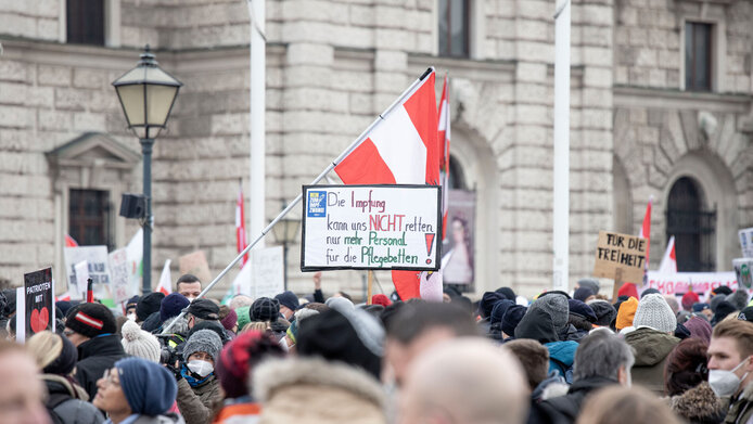 Demonstrierende, mit Österreichfahne und Schildern gegen die Corona-Impfung