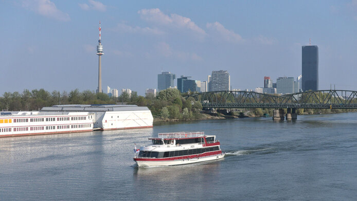 Schiff fährt entlang der Donau in Wien mit Donaucity im Hintergrund