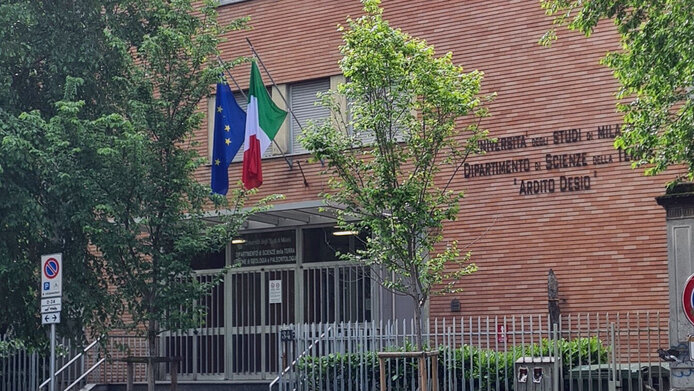 Brick building with trees and flags in the foreground