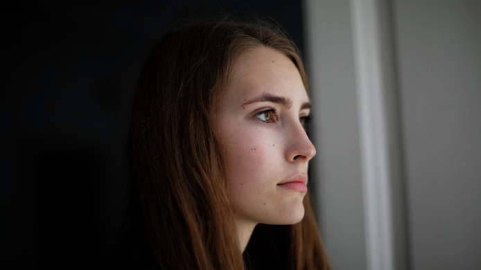 Nachdenkliche Frau aus dem Fenster schauend.