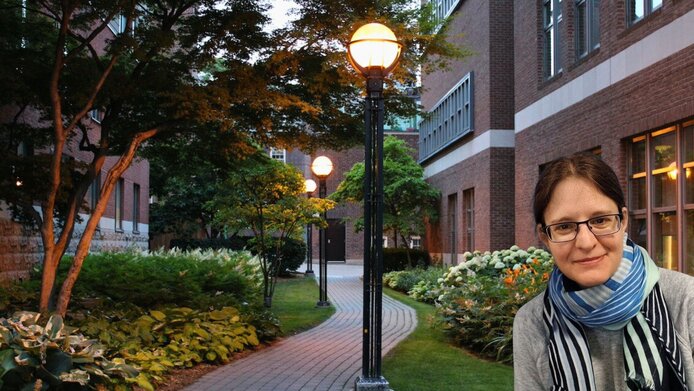 Researcher with old brick buildings of St. George Campus Toronto in the background