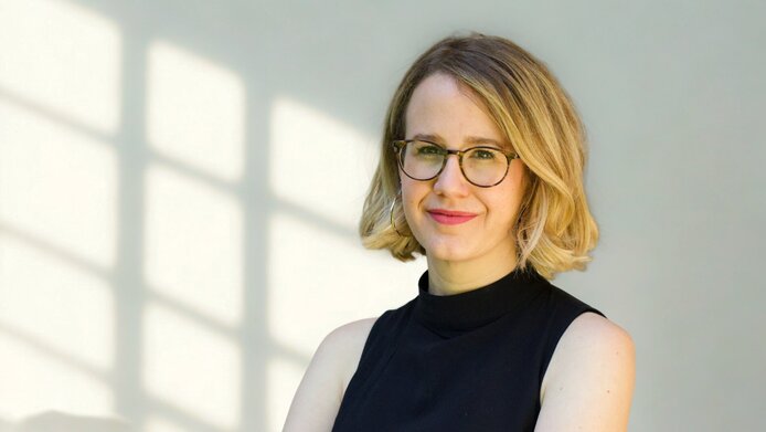 Frau mit dunkelblondem Pagenschnitt und Brille, ärmelloses schwarzes Top