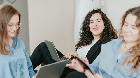 Drei junge Frauen arbeitend mit Laptops auf den Knien