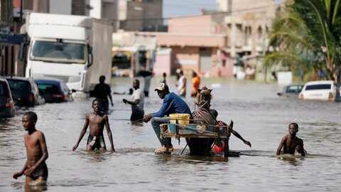 Flooded street in Dakar, West Africa – People wading through water that reaches up to their waists