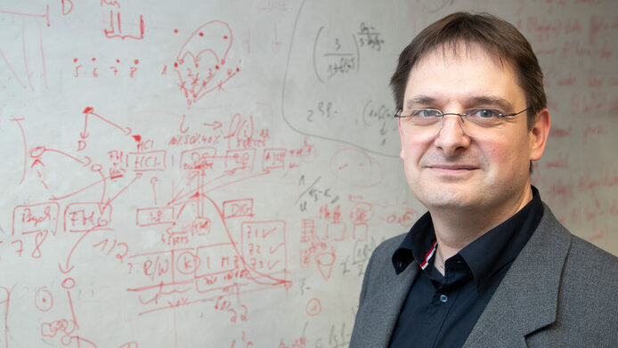 Porträt des Mathematikers Robert Elsässer vor Tafel mit Kurven und Berechnungen