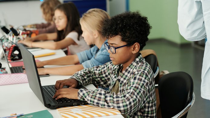 Kinder am Laptop schreibend in einem Klassenzimmer