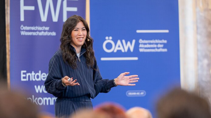 Junge asiatische Frau lächelnd, trägt auf einer Bühne vor. 