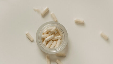 Tablets in capsule form scattered around the table and in a glass container