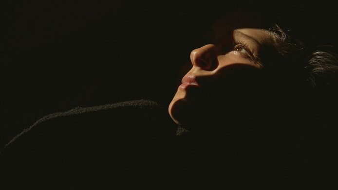 Woman in a dark room staring at the ceiling