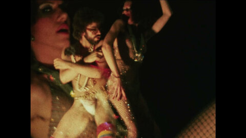 Film still from the queer community shows two women and a man in lascivious poses and costumes